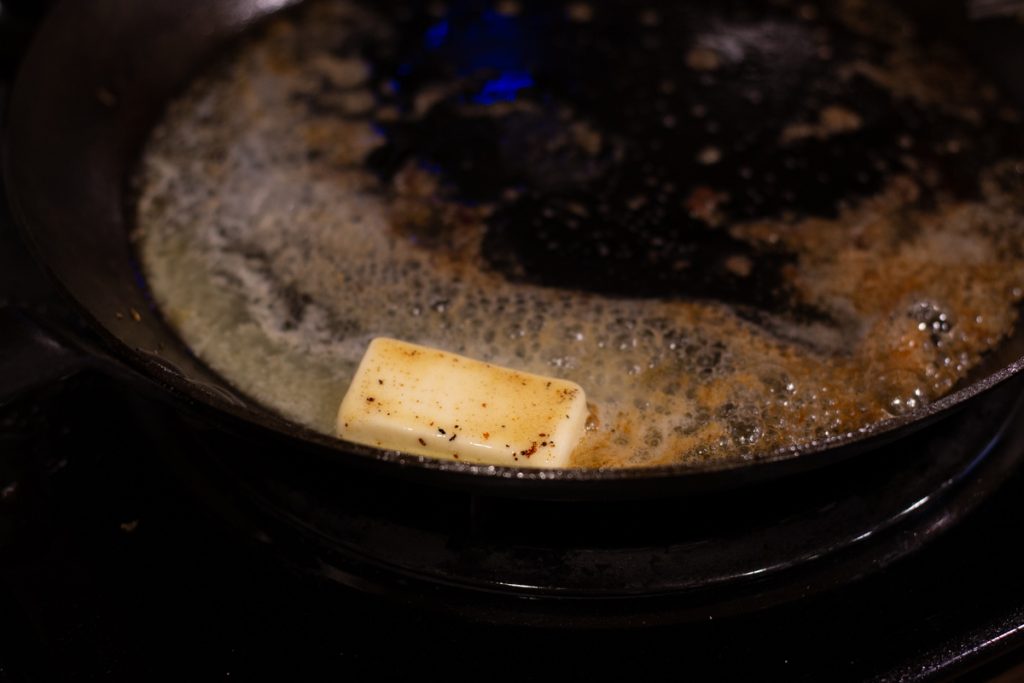 butter melting in cast iron skillet on stove