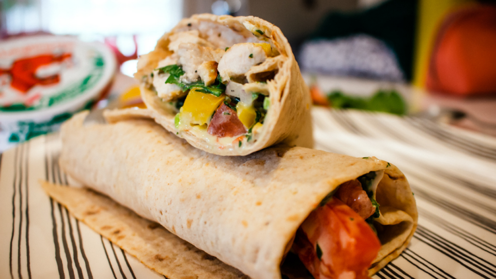grilled chicken wrap for lunch on plate with veggies and jalapeno dressing inside