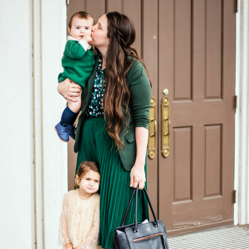 mother holding baby boy and posing with little girl in front of church door