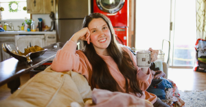 jessica savoy brown sitting on couch with laundry and coffee cup