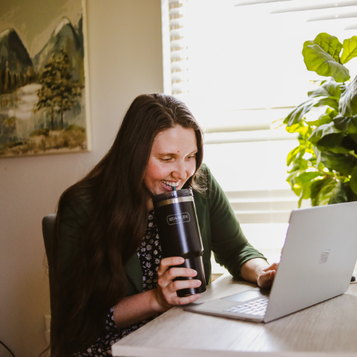 woman working on laptop drinking coffee smiling
